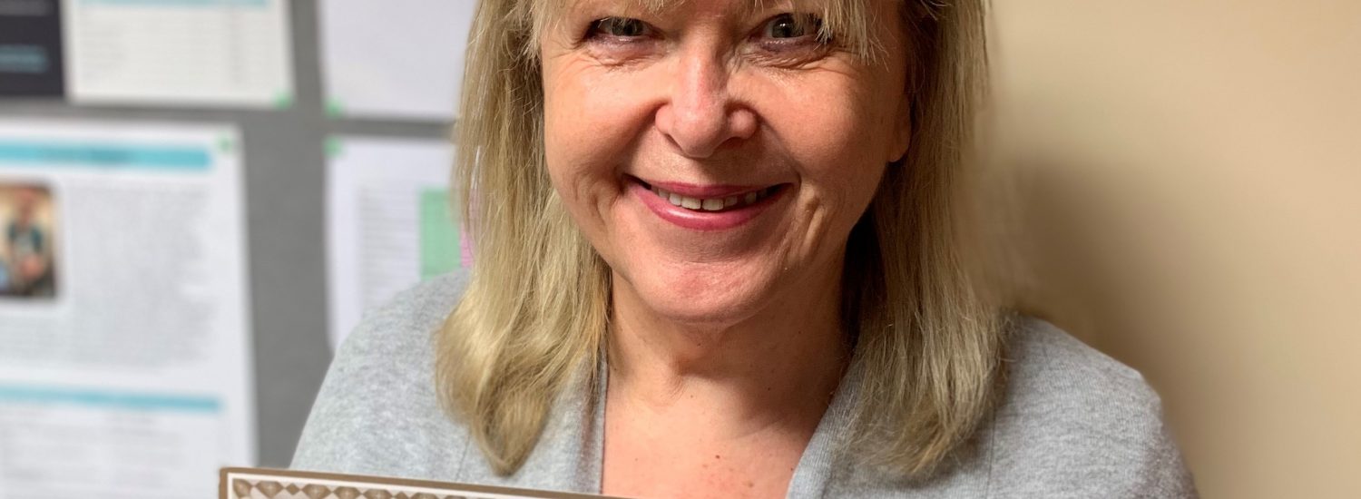 Image shows vet receptionist Sheila Potter holding her gold certificate from the BVRA