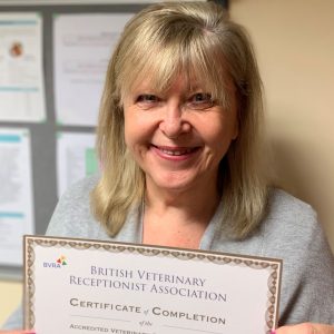 Image shows vet receptionist Sheila Potter holding her gold certificate from the BVRA