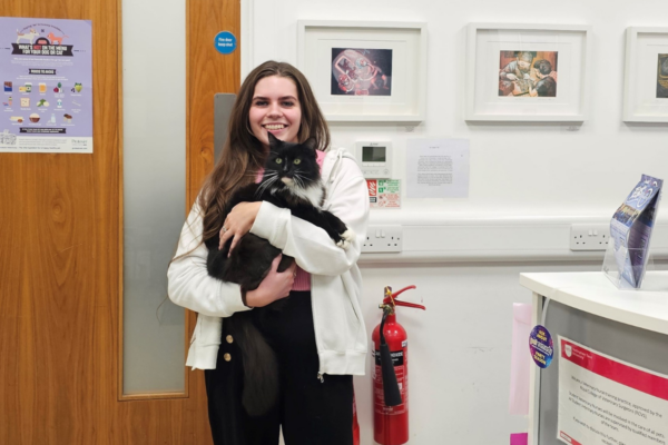 woman in vet practice holding black cat